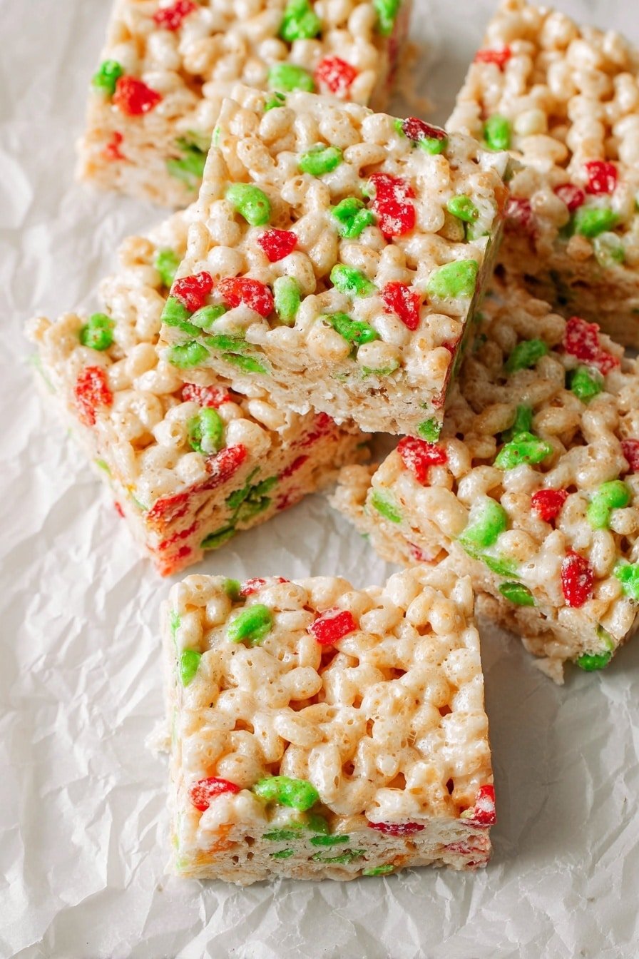 The image shows several square treats made from puffed rice cereal mixed with a sticky, pale beige binder. Each treat has bright red and green cereal pieces scattered evenly throughout, giving a colorful and festive look. The squares are stacked and slightly overlapping each other on a crinkled white parchment paper that rests on a white marbled surface. The texture of the treats looks soft, sticky, and slightly shiny with visible puffed rice grains tightly packed together. photo taken with an iphone --ar 2:3 --v 7