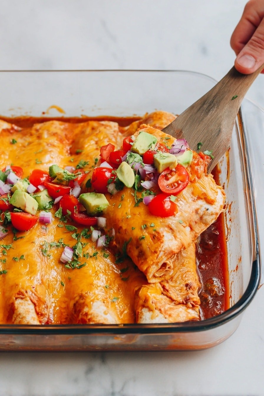 In a clear glass baking dish, two enchiladas sit side by side, covered with a melted golden-orange layer of cheese that has a slightly bubbly and smooth texture. The enchiladas are topped with small, bright red slices of cherry tomatoes, light green chunks of avocado, and tiny pieces of purple onion mixed with finely chopped green herbs. The dish rests on a white marbled surface, and a wooden-handled spatula lifts one enchilada from the dish, held by a woman's hand in the top right corner of the image. The sauce at the bottom of the baking dish is rich red with visible chunks of ingredients underneath the enchiladas. photo taken with an iphone --ar 2:3 --v 7