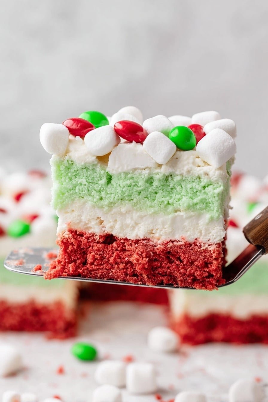 A square layered dessert on a white plate with three distinct layers: the bottom layer is a red crumbly base, the middle layer is thick white cream, and the top layer is a smooth green cream. The dessert is topped with small white marshmallows and scattered red and green round candies. In the background, there is a white mug full of mini white marshmallows and a clear dish showing the same layered dessert with similar toppings. The surface is a white marbled texture. photo taken with an iphone --ar 2:3 --v 7