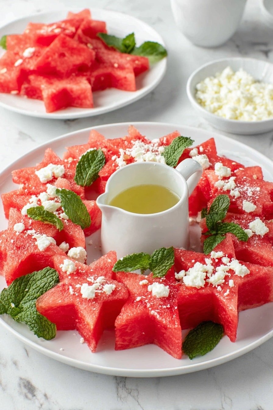A white plate with a wreath made of star-shaped watermelon pieces layered with fresh green mint leaves, sprinkled with small white crumbles of cheese on top; in the middle of the plate sits a small white pitcher with light golden liquid inside. In the background, there are two white bowls, one filled with more watermelon pieces and the other with more cheese crumbles, all placed on a white marbled surface. photo taken with an iphone --ar 2:3 --v 7