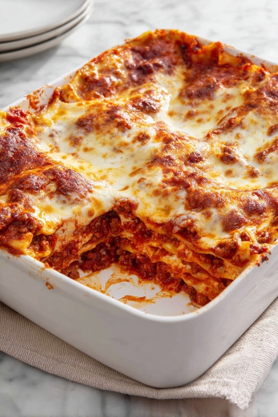 A white baking dish holds a square lasagna with four visible layers: bright red tomato sauce mixed with cooked ground meat, creamy white cheese layers, and melted golden-brown cheese on top that looks bubbly and slightly crispy. The edges of the dish have some sauce drips, and the inside layers show a mix of sauce, cheese, and pasta sheets. The dish sits on a light beige cloth on a white marbled surface. Photo taken with an iphone --ar 2:3 --v 7