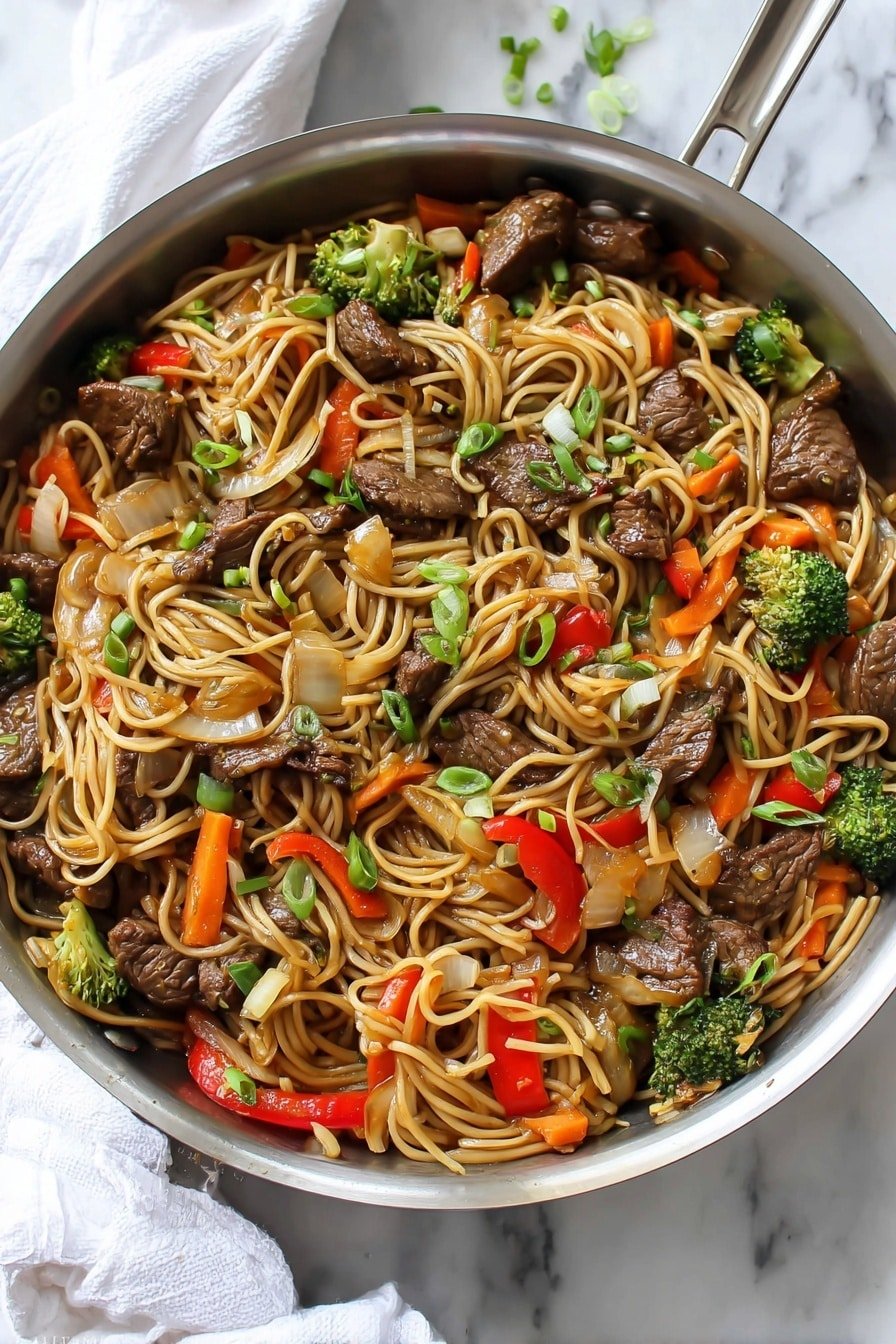 The image shows a stainless steel pan filled with a colorful stir-fry. The base layer consists of long, thin noodles that are light brown and twisted around the pan. Mixed in are pieces of cooked beef that are dark brown and glossy. There are bright green broccoli florets and small orange carrot sticks, adding a fresh contrast. Chunks of red bell pepper and translucent white onion slices are scattered throughout. Small bits of chopped green scallions are sprinkled on top, giving a fresh garnish look. The pan sits on a white marbled surface with a white cloth and metal spoon handle visible at the top right corner. photo taken with an iphone --ar 2:3 --v 7