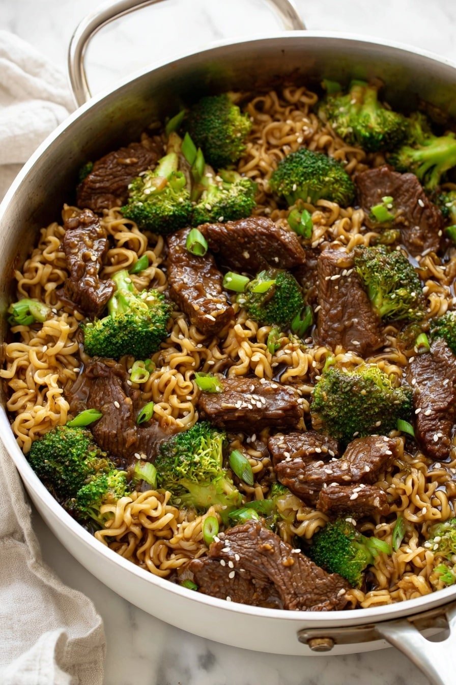 The image shows a metal pan filled with a stir-fry dish consisting of three main layers: the bottom layer has cooked wavy ramen noodles in a light brown sauce, the middle layer has bright green broccoli florets evenly spread, and the top layer has shiny, dark brown pieces of beef coated in sauce, sprinkled with small white sesame seeds and chopped green onions. The pan is placed on a white marbled surface with a white cloth partially visible in the background. The photo taken with an iphone --ar 2:3 --v 7