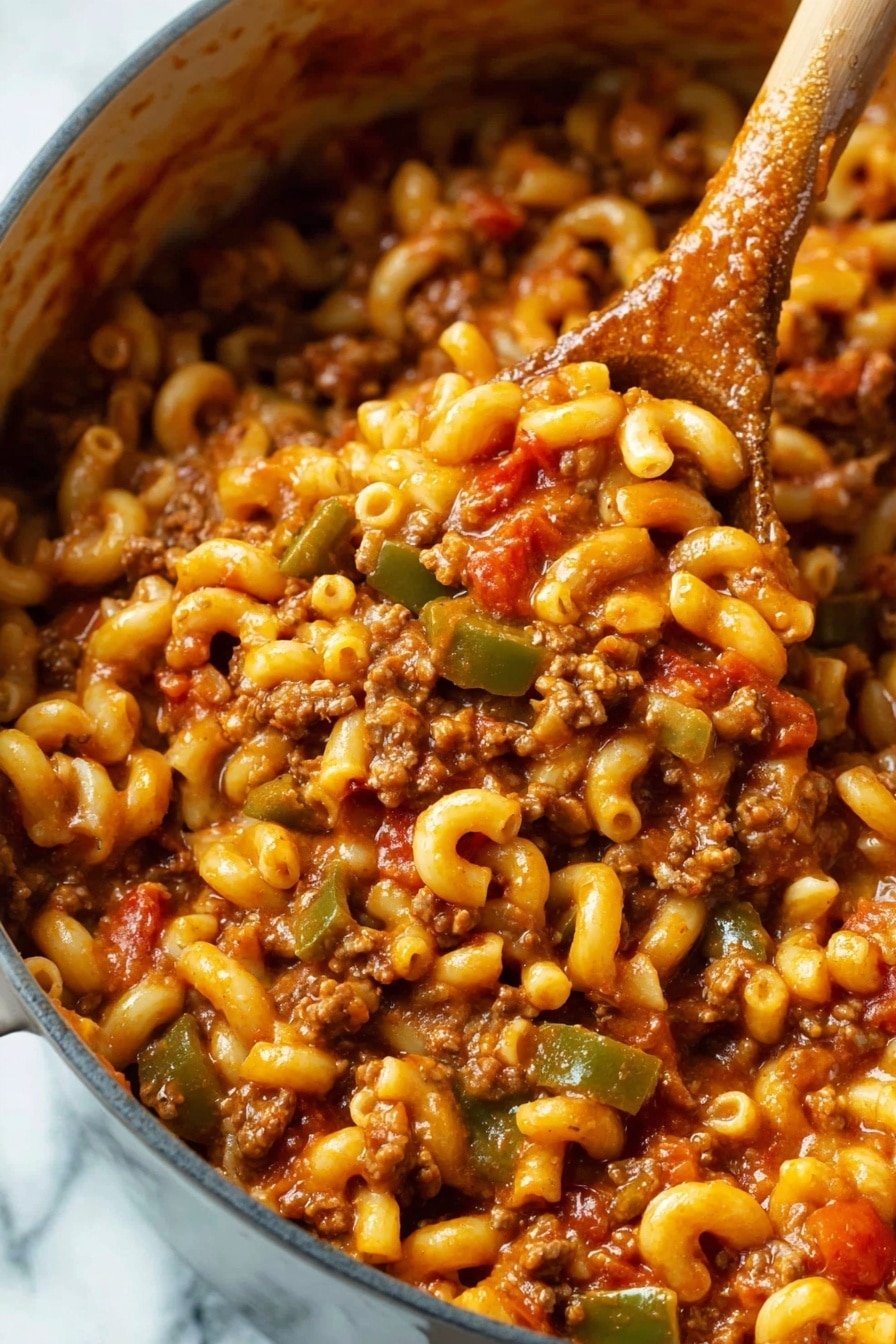 A close-up image shows a pot full of macaroni pasta mixed with ground meat, diced green bell peppers, and chunks of red tomatoes, all coated in a rich, reddish-brown sauce. The macaroni is soft and slightly curved, with the meat and vegetables evenly spread throughout. A wooden spoon is scooping the mixture from the pot, with the spoon's surface partially stained by the sauce. The background has a white marbled texture. Photo taken with an iphone --ar 2:3 --v 7
