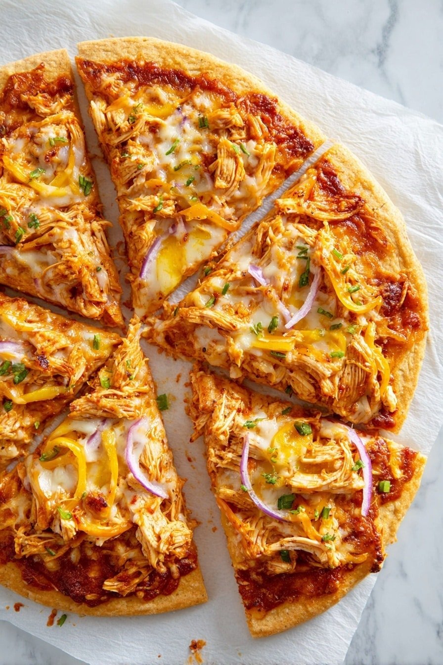 The image shows a pizza cut into six slices on white parchment paper over a white marbled surface. The pizza has a thick golden-brown crust as the base layer, topped with a rich reddish-orange sauce spread evenly. There is a generous layer of melted white and orange cheese scattered on top, with visible patches of melted texture. Shredded light brown chicken pieces are spread over the cheese, along with slices of yellow peppers and thin red onion strips. Small green herb bits are sprinkled on the pizza, adding a fresh contrast of color. One slice is slightly separated from the others, revealing the melted cheese stretching a little. photo taken with an iphone --ar 2:3 --v 7