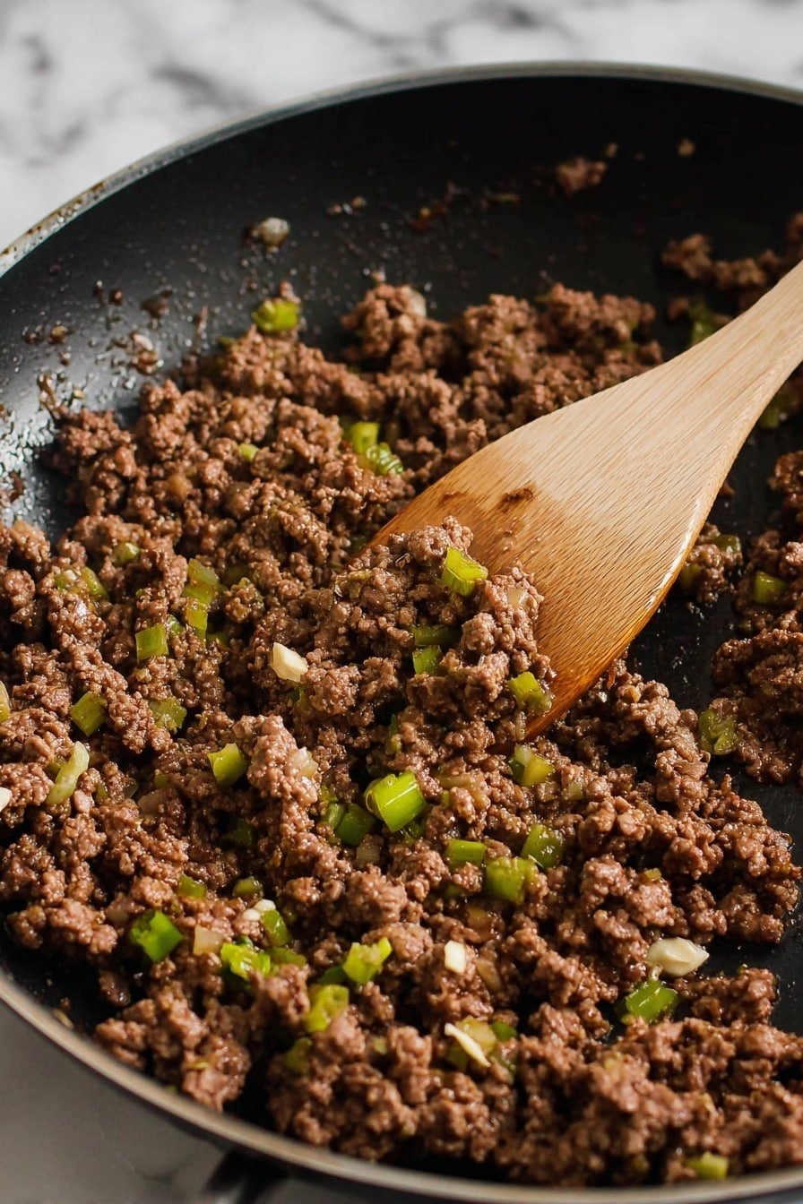 The image shows a close-up of cooked ground meat mixed with small pieces of green onions and tiny bits of white garlic in a black frying pan. The meat is brown and looks moist with some shiny sauce around it. A wooden spatula is partially in the pan, resting over the meat as if stirring it. The background has a white marbled texture. photo taken with an iphone --ar 2:3 --v 7
