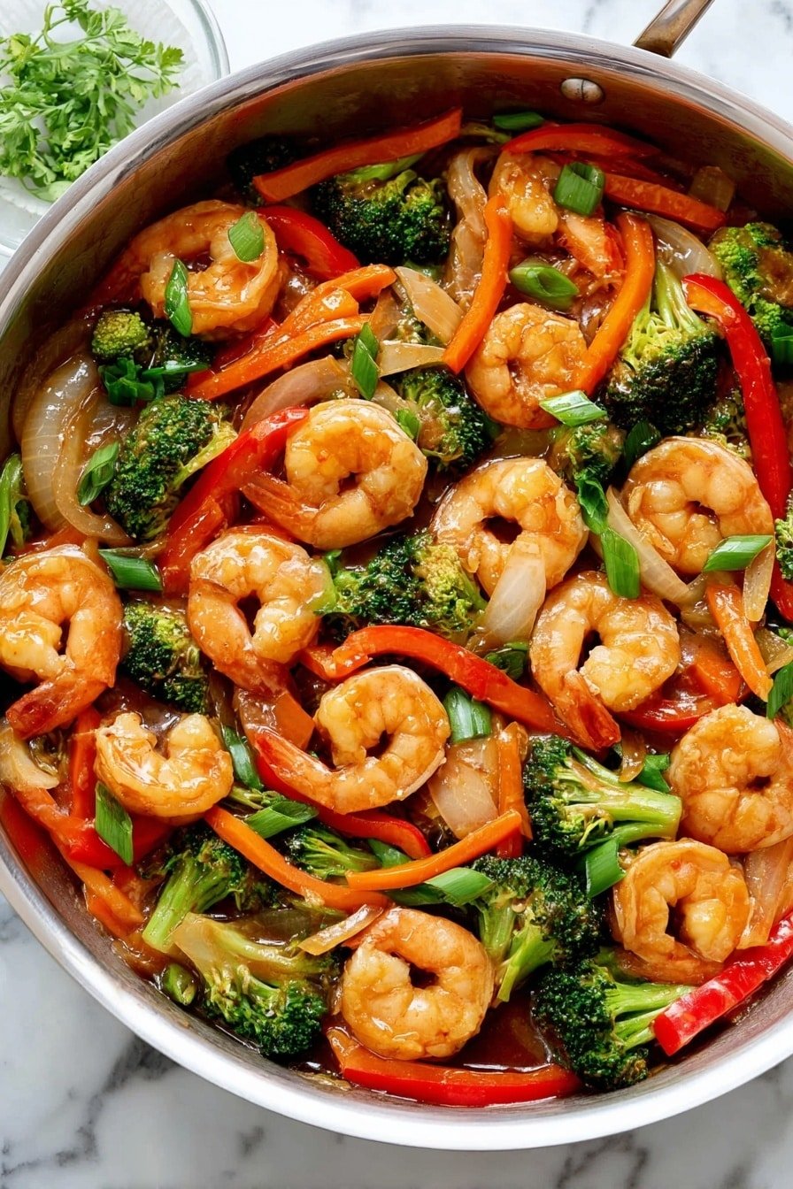 A large silver pan filled with cooked shrimp and colorful vegetables. The shrimp are light orange with a glossy shine, spread evenly throughout the pan. Mixed in are bright green broccoli florets, long thin orange carrot sticks, red bell pepper strips, and pieces of onion with a pale translucent look. The vegetables and shrimp are coated in a glossy sauce, giving a slightly wet texture. The background shows a white marbled surface with a few small green herb pieces near the top. Photo taken with an iphone --ar 2:3 --v 7