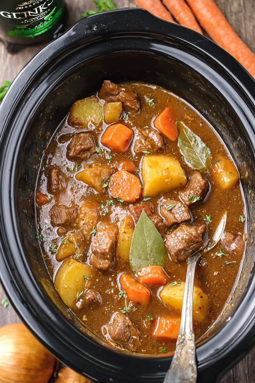 The image shows a black slow cooker filled with a thick stew. The stew has chunks of brown meat, small orange carrot slices, and pieces of light yellow potatoes in a glossy brown sauce. There are also whole bay leaves and sprigs of green herbs mixed in. A silver spoon is partially dipped in the stew, resting on the side of the cooker. Around the slow cooker, there are whole carrots, a yellow onion, and a dark bottle of Guinness beer placed on a wood texture surface. photo taken with an iphone --ar 2:3 --v 7