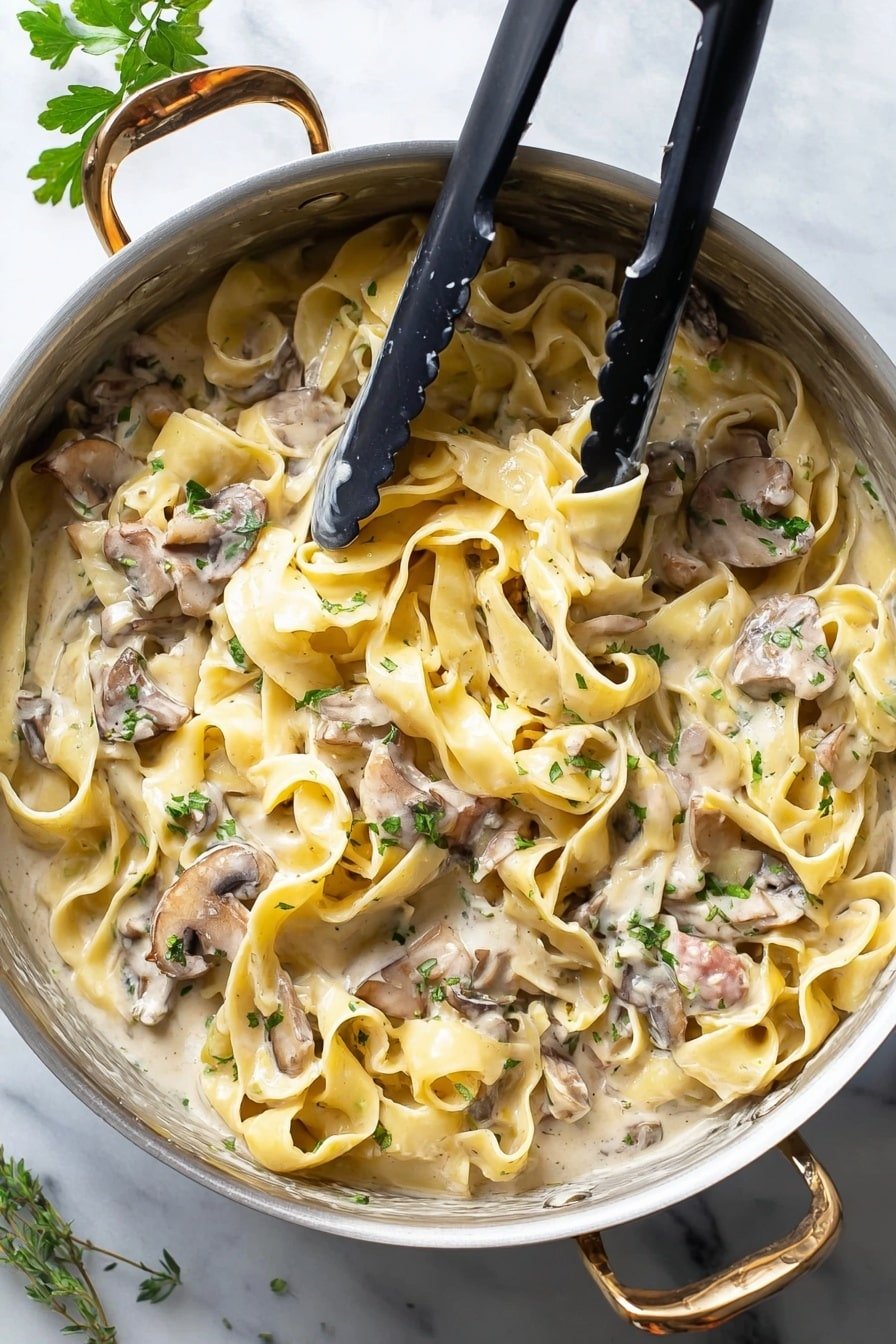 A white pot filled with wide, flat pasta ribbons in a creamy light beige sauce. The pasta layers are soft and slightly curled, mixed with sliced brown mushrooms scattered evenly throughout. Small bits of light pink meat and green herbs are visible on top and within the sauce, giving it texture and color contrast. Two black tongs rest inside the pot above the pasta. The pot sits on a white marbled surface, with some green leaves partially visible in the upper left corner. photo taken with an iphone --ar 2:3 --v 7