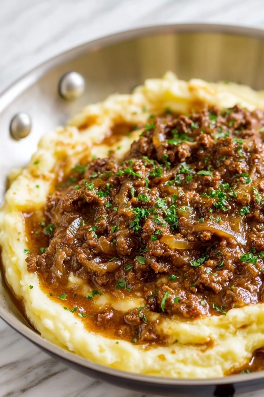 A close-up view of a creamy mash potato base forms the bottom layer, soft and pale yellow with a smooth texture. On top, there is a thick layer of brown ground meat mixed with a rich, glossy gravy that has small bits of onion visible, adding texture. The meat mixture is garnished lightly with finely chopped green herbs that add a touch of color. All of this is served in an ornate white bowl, placed on a white marbled texture. photo taken with an iphone --ar 2:3 --v 7