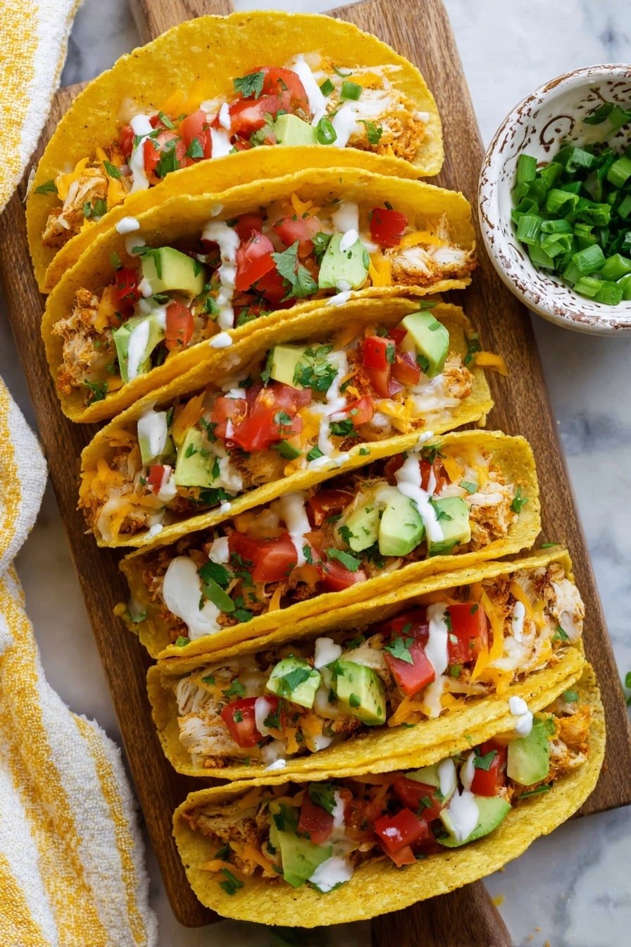 Five yellow corn taco shells filled with a mix of white fish flakes and melted orange cheddar cheese form the base layer. On top, small cubes of bright red tomatoes and light green avocado pieces are scattered, adding fresh color. Chopped green herbs and a drizzle of white sauce cover the fillings. The tacos are placed closely in a stacked row on a wooden board next to a small ornate white bowl filled with chopped green onions. The scene sits on a white marbled surface with a yellow and white striped cloth peeking from the left side. Photo taken with an iphone --ar 2:3 --v 7