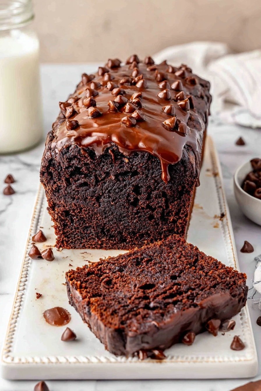 A rich, dark chocolate loaf cake sits on an ornate white rectangular board, with one thick slice lying flat in the front and another slice leaning on the cake itself. The cake is covered with a glossy chocolate glaze that drips slightly down the sides and is topped with scattered chocolate chips. The inside of the cake looks moist and dense with a fine texture, and more chocolate chips are embedded within the slices. Around the board, there are loose chocolate chips scattered, enhancing the chocolate theme. The setting has a soft, neutral tone with a white marbled texture beneath the board and a glass jar with milk placed on the left side in the background. photo taken with an iphone --ar 2:3 --v 7