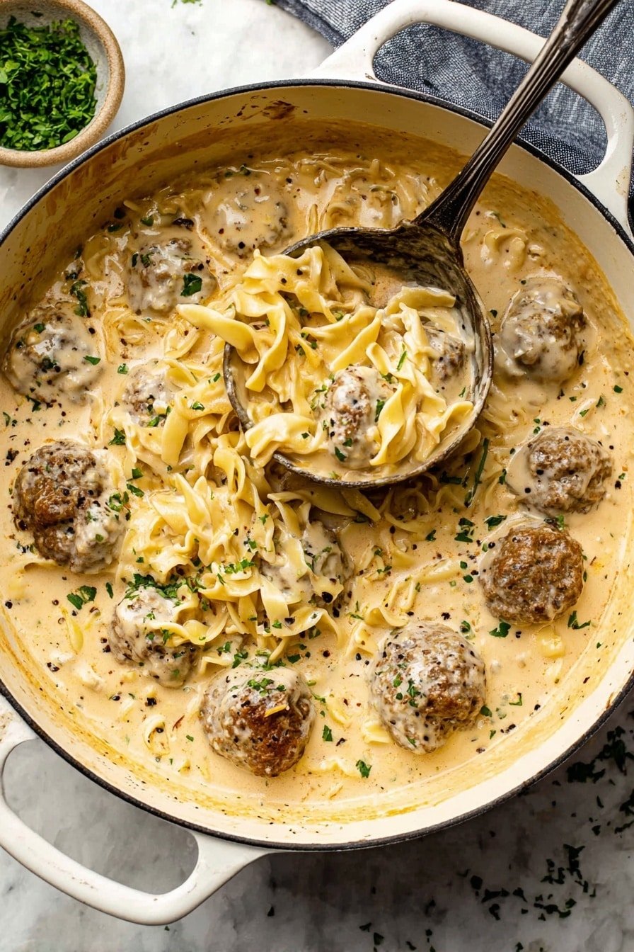 A large ornate white pot filled with a creamy beige sauce that has visible specks of black pepper and green herbs scattered throughout. Inside the sauce, there are several round brown meatballs with a rough texture, partially submerged. Nestled among the meatballs are short yellowish pasta noodles, mixed well within the creamy layer. A large, dark metal ladle is scooping up some noodles and one meatball, showing the thick texture of the sauce. The pot sits on a white marbled surface, with a small bowl of chopped green herbs nearby. photo taken with an iphone --ar 2:3 --v 7