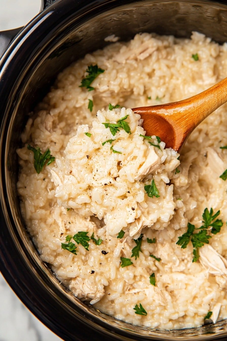 A close-up view inside a shiny metal pot showing creamy risotto with soft, light beige rice grains mixed with small white pieces of chicken. The risotto has a smooth, thick texture with fresh green parsley leaves sprinkled evenly on top as garnish. A wooden spoon with a glossy light brown handle is partially dipped into the risotto, lifting some of the rice and chicken mix. The dish appears warm and rich with subtle black pepper specks for added detail. The background is a white marbled texture. photo taken with an iphone --ar 2:3 --v 7