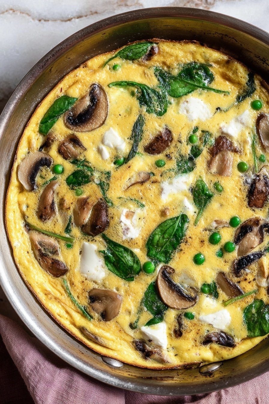 The image shows a cooked frittata in a dark pan with a golden-yellow egg base that looks soft and slightly bubbly. Scattered throughout the frittata are several clusters of white, creamy cheese, dark brown and tan slices of mushrooms, small bright green peas, and fresh green spinach leaves. The edges of the frittata have a light brown crust, creating a contrast with the creamy inside. The pan rests on a white marbled texture with a soft pink cloth nearby. Photo taken with an iphone --ar 2:3 --v 7