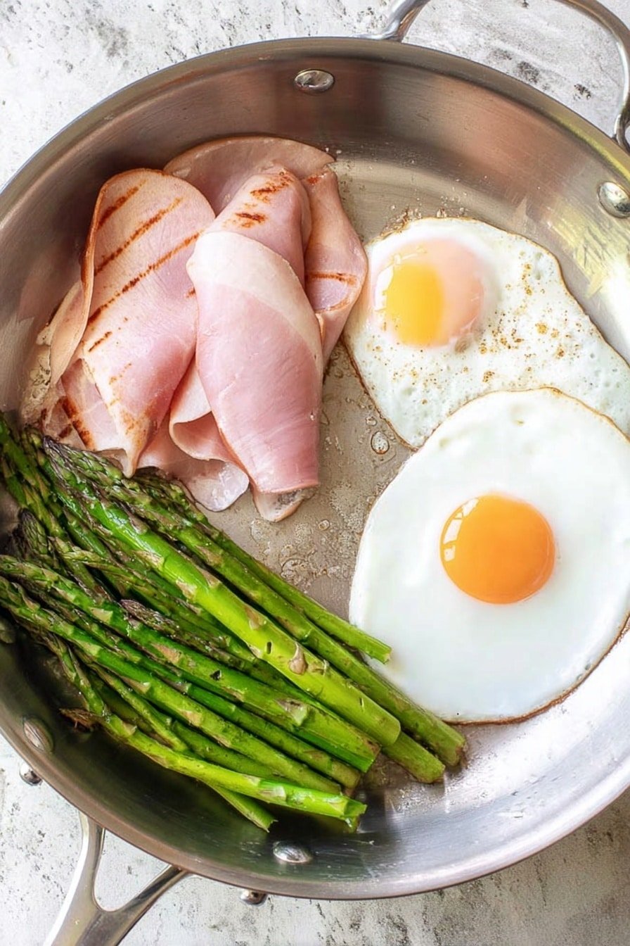 In a silver metal frying pan, there are two fried eggs with bright white edges and pale yellow yolks, one near the top right and another near the bottom right. To the left of the eggs, there are three slices of light pink ham with some browned grill marks stacked partially over each other. Below the ham, a bunch of green asparagus spears are placed close together, showing a fresh and slightly shiny texture. The pan rests on a white marbled textured surface. photo taken with an iphone --ar 2:3 --v 7