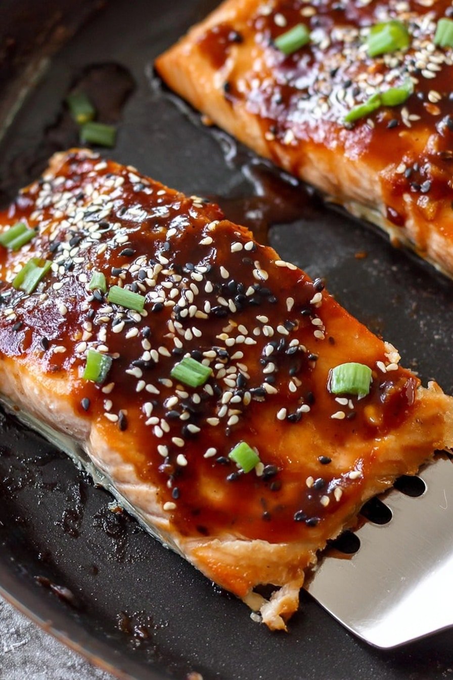 The image shows two pieces of cooked fish with a shiny, dark brown glaze spread over the surface. The top layer of sauce is glossy and thick, with seeds of white and black sesame sprinkled on top. Small, bright green onion pieces are scattered over the sauce. The fish is on a black pan, and a metal spatula is partly under the fish piece on the right side. The fish looks tender and has a light, slightly browned underside. The background is changed to a white marbled texture. photo taken with an iphone --ar 2:3 --v 7