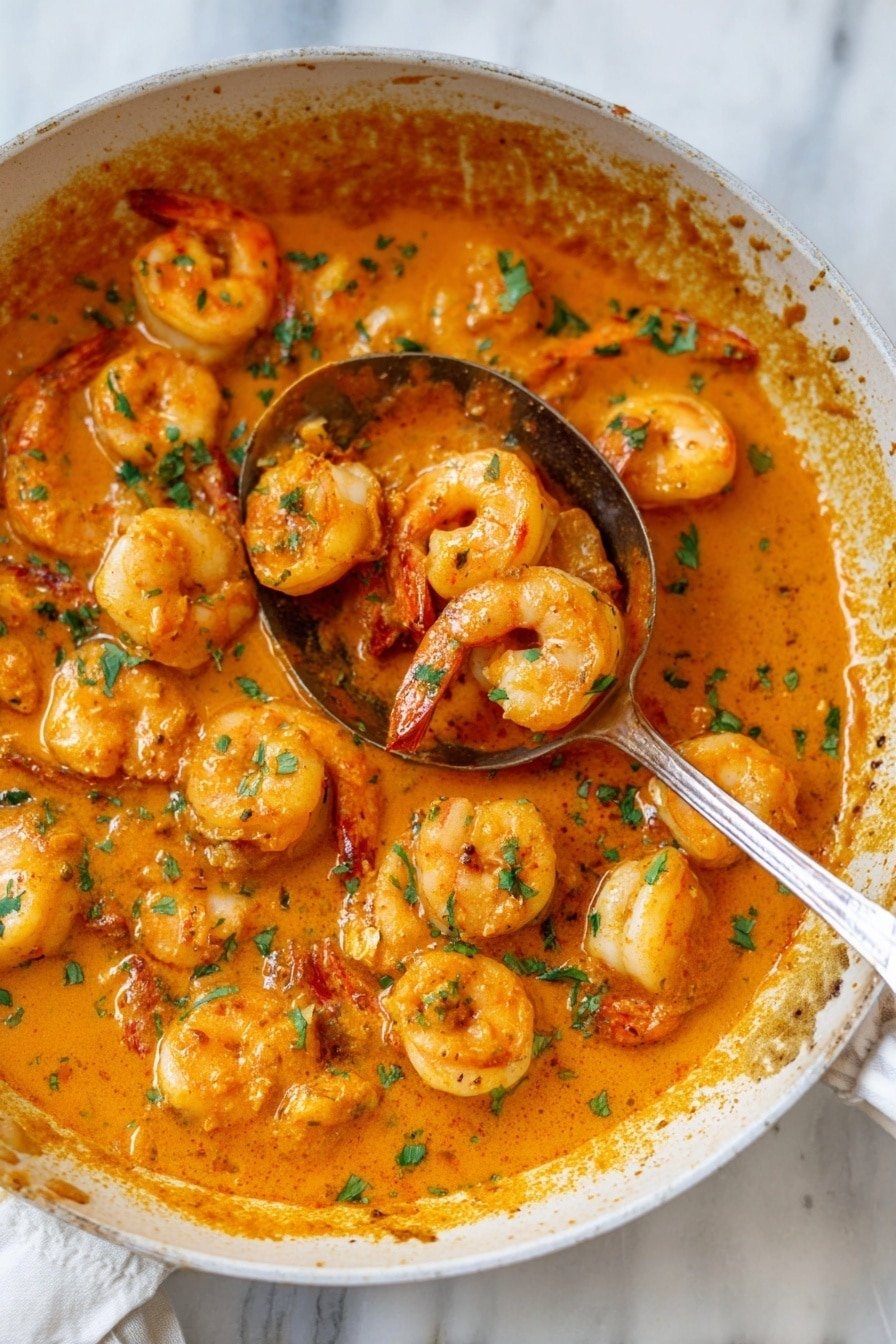 A metal pan holding a rich, thick orange sauce with many cooked shrimp in it, each shrimp is light orange with a smooth texture. The sauce covers the bottom and sides of the pan and has small green chopped herbs sprinkled evenly on top. A wooden spoon with a brown grain pattern is scooping some shrimp from the sauce, showing the shrimp's curved shape. The pan sits on a white marbled surface. photo taken with an iphone --ar 2:3 --v 7