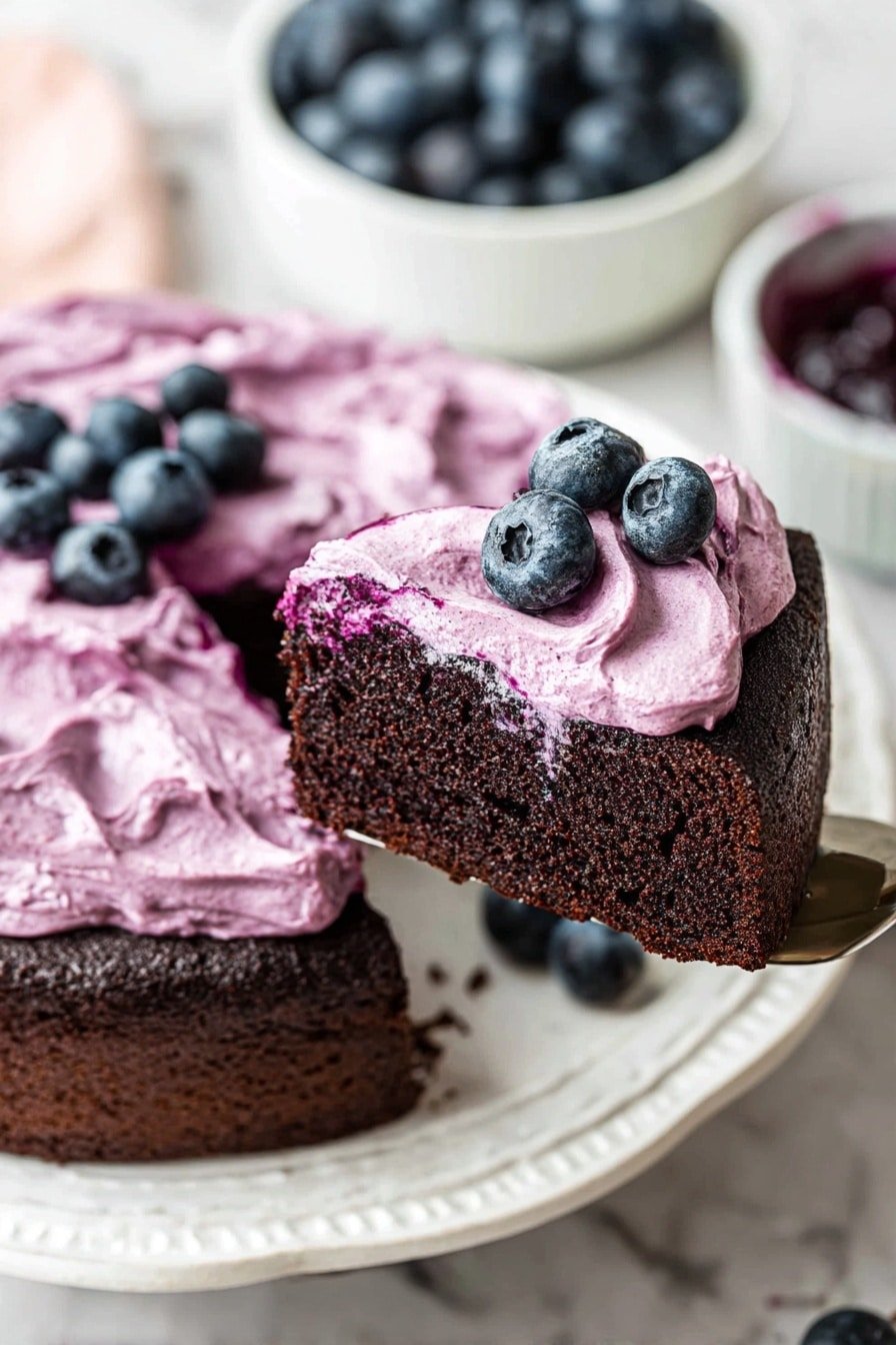 A dark brown chocolate cake slice with a thick, creamy layer of light purple blueberry frosting spread unevenly over the top, creating soft waves and swirls. Three fresh blueberries sit on the frosting near the slice's edge. The slice rests on a white plate with a slight glossy texture on a white marbled surface. In the background, a white bowl full of fresh blueberries and another white bowl with blueberry jam slightly out of focus can be seen. Photo taken with an iphone --ar 2:3 --v 7