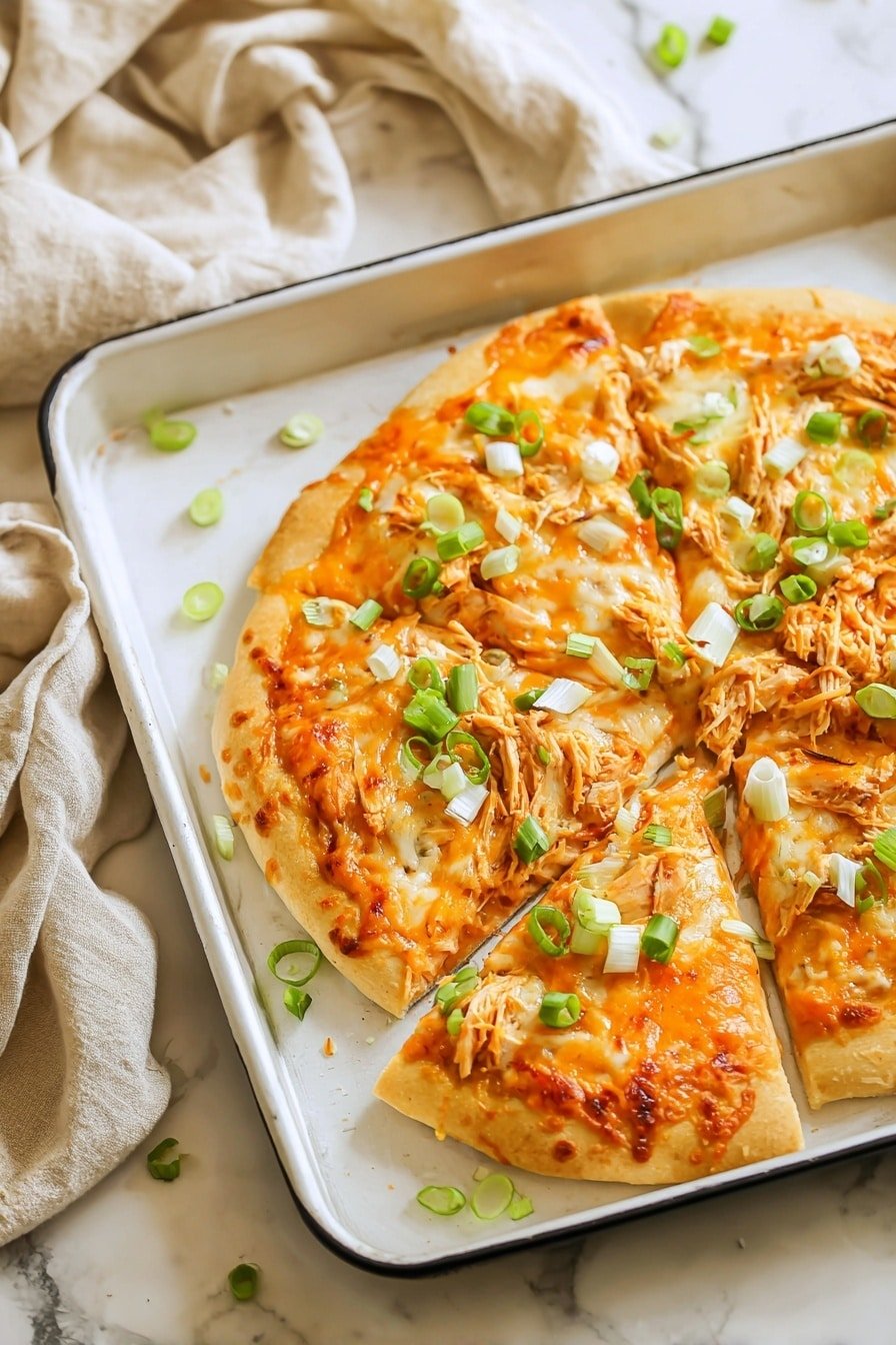A white baking tray holds a pizza with a golden brown crust as the first layer. The second layer is melted orange cheese covering the pizza evenly. The third layer is shredded light orange chicken pieces scattered on top. Green sliced scallions are sprinkled over the cheese and chicken as the final layer, adding bright green spots all over. A metal spatula lifts one slice from the tray, showing the layers clearly. The tray sits on a white marbled surface with a beige and red cloth in soft folds in the background. photo taken with an iphone --ar 2:3 --v 7