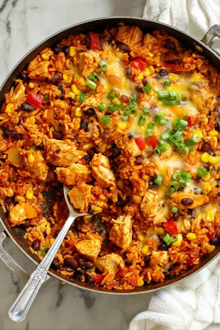 A large skillet filled with a layered dish starting with a base of orange-red seasoned rice mixed with black beans and small chunks of red and yellow bell peppers. Scattered over the rice are pieces of cooked white chicken, coated slightly in sauce. The top layer is melted golden cheese with a creamy texture, partially covering the rice and chicken. Bright yellow corn kernels and sliced bright green onions are spread across the surface, adding color and freshness. A silver spoon rests inside the skillet, partially scooping the dish. The skillet sits on a white marbled texture with a white cloth nearby. photo taken with an iphone --ar 2:3 --v 7